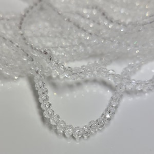 May include: A strand of clear crystal beads, with a faceted finish, strung on a thin wire. The beads are small and uniform in size.