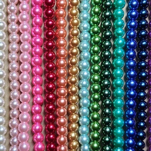 May include: Rows of colorful beads in various shades, including black, white, pink, red, orange, green, blue, purple, and brown. The beads are round and appear to be strung together, creating a vibrant display of colors.