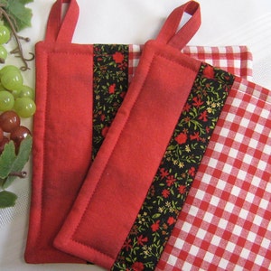 May include: Two red pot holders with floral fabric trim and a red and white gingham fabric backing.