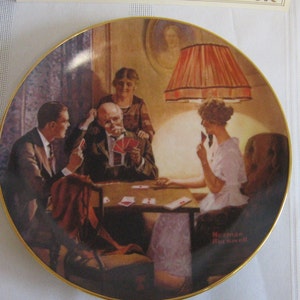 May include: A vintage-style collectible plate featuring a Norman Rockwell painting of four people playing cards around a table. The scene is set in a dimly lit room with a lampshade casting a warm glow. The plate is decorated with a gold rim and the artist's signature.