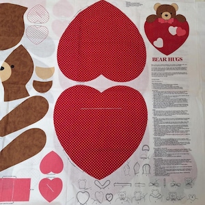 May include: A white fabric panel featuring printed sewing patterns for a stuffed bear and hearts. The design includes brown bear body parts, large red heart shapes with white polka dots, and printed instructions titled BEAR HUGS with diagrams.