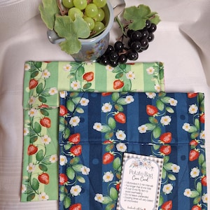 Peut inclure: Deux sacs à pommes de terre en tissu carré avec un motif de fraises et de fleurs blanches sur des fonds rayés. Un sac est vert clair, l'autre est bleu foncé. Une petite carte d'entretien blanche avec le texte Potato Bag Care Card est jointe.