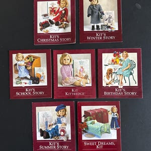 May include: Seven books with red covers featuring illustrations of a doll in various settings. Titles include "Kit's Christmas Story," "Kit's Winter Story," "Kit's School Story," "Kit Kittredge," "Kit's Birthday Story," "Kit's Summer Story," and "Sweet Dreams, Kit."