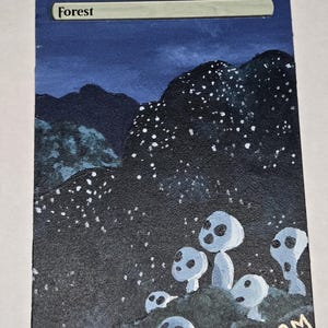 May include: A rectangular trading card featuring a hand-painted scene of a dark forest at night with white glowing specks and several small, pale, round-headed figures with dark eye and mouth holes. The word Forest is printed at the top.