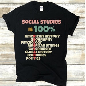 Op de afbeelding: Zwart T-shirt met de tekst "SOCIAL STUDIES IS 100%" en een lijst met vakken, waaronder Amerikaanse geschiedenis, geografie, psychologie, Amerikaanse studies, overheid, wereldgeschiedenis, economie en politiek.