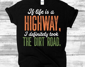 May include: Black t-shirt with a distressed orange and green graphic that reads "If life is a HIGHWAY, I definitely took THE DIRT ROAD."