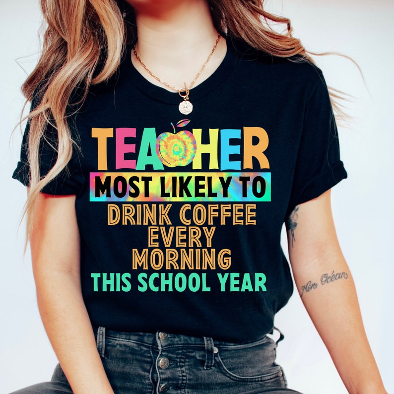 以下が含まれることがあります： 「Teacher most likely to drink coffee every morning this school year」というテキストが書かれた、カラフルなタイダイ柄の黒いTシャツです。