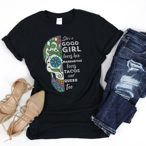 May include: Black t-shirt with a colorful sugar skull graphic and the text "She's a good girl loves her margaritas loves tacos and queso too".