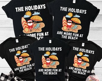 May include: Four black t-shirts with a white graphic design of Santa Claus surfing on a surfboard with the text "The Holidays Are More Fun At The Beach".