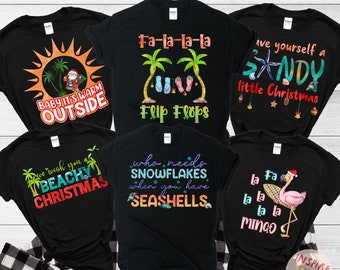 May include: Six black t-shirts with different Christmas-themed designs featuring palm trees, flip flops, snowflakes, seashells, a flamingo, and a Santa Claus. The text on the shirts includes "Baby it's warm outside", "We wish you a beachy Christmas", "Fa-la-la-la Flip Flops", "Who needs snowflakes when you have seashells", "Have yourself a sandy little Christmas", and "La fa la la la mingo".