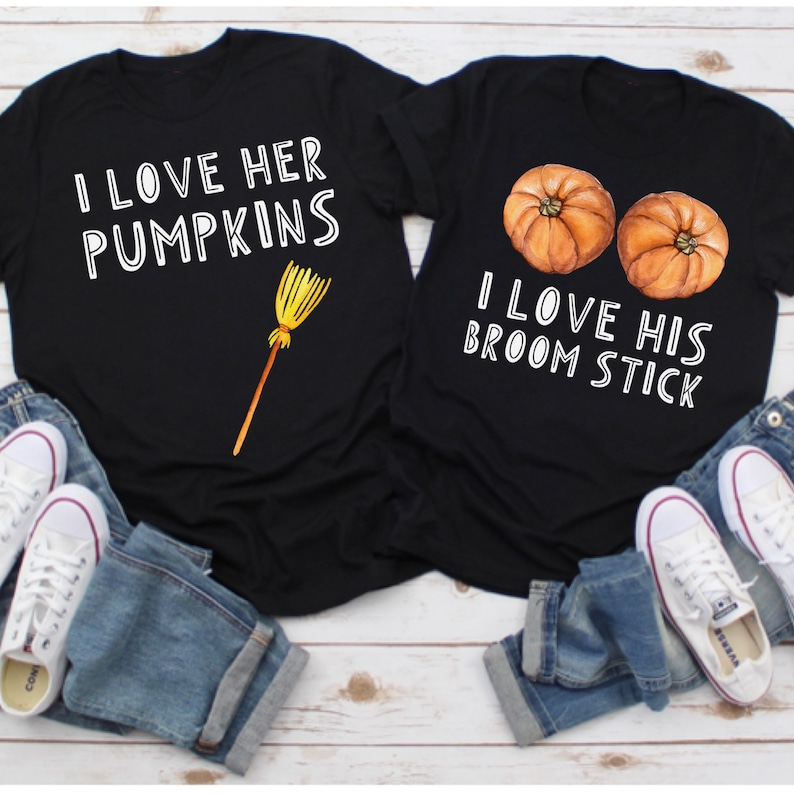 May include: Two black t-shirts with white text and Halloween-themed graphics. One shirt says "I LOVE HER PUMPKINS" with a broom graphic. The other says "I LOVE HIS BROOM STICK" with two pumpkin graphics. Both shirts are paired with blue jeans and white sneakers.