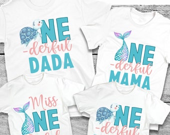 May include: Four white t-shirts with a blue and pink design. The shirts say "One-derful Dada", "One-derful Mama", "Miss One-derful", and "One-derful Brother".
