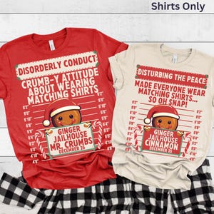 May include: Two Christmas-themed t-shirts, one red and one cream, with humorous text and gingerbread man graphics. The red shirt reads "Disorderly Conduct" and the cream shirt says "Disturbing the Peace". Both shirts have a "Ginger Jailhouse" theme.