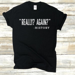 May include: Black t-shirt with white text that reads "Really? Again?" - History.