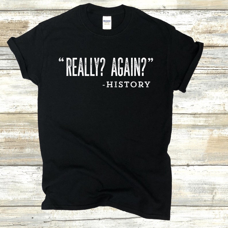May include: Black t-shirt with white text that reads "Really? Again?" - History.