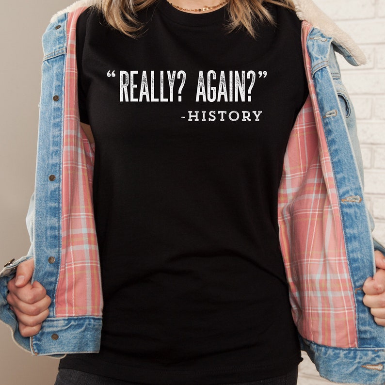 May include: Black t-shirt with white text that reads "Really? Again? - History"