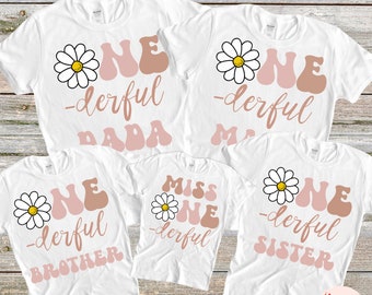 May include: Set of five white t-shirts with a daisy and the text "One-derful" in pink and brown. The shirts say "One-derful Dada", "One-derful Mama", "One-derful Brother", "Miss One-derful", and "One-derful Sister".