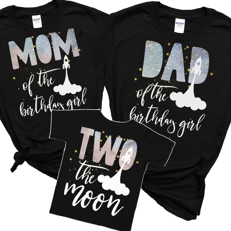 Pode incluir: Tr&ecirc;s camisetas pretas com tema espacial. A primeira camiseta diz "M&atilde;e da menina do anivers&aacute;rio" com um foguete e estrelas. A segunda camiseta diz "Pai da menina do anivers&aacute;rio" com um foguete e estrelas. A terceira camiseta diz "Dois a lua" com um foguete e estrelas.
