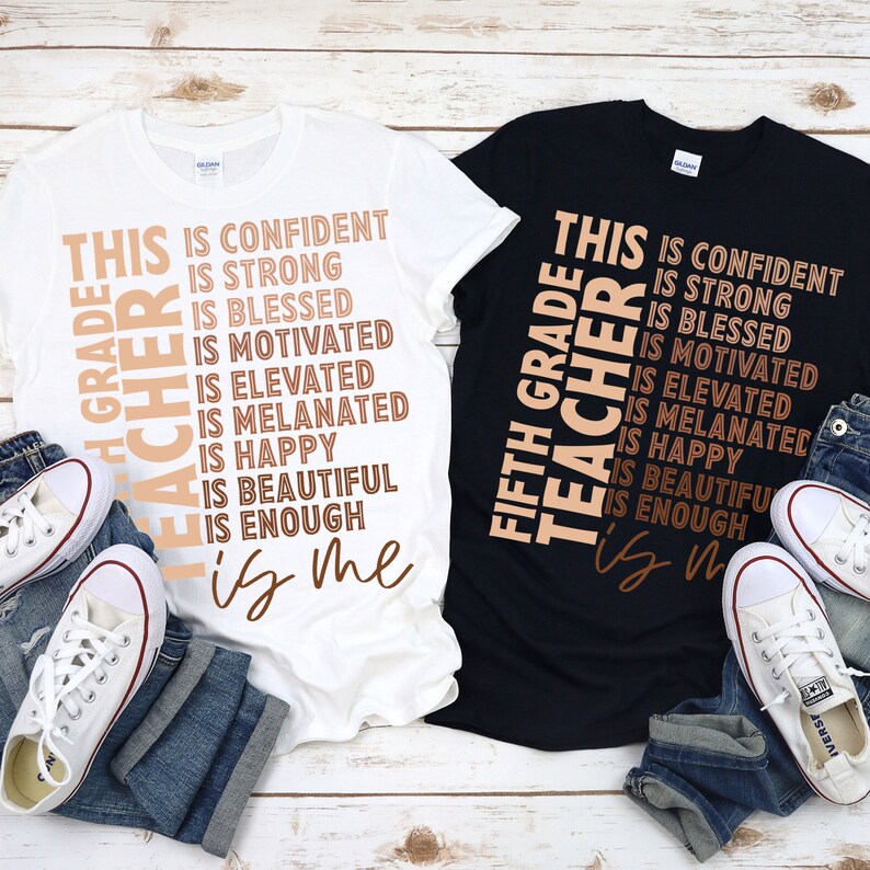 Puede incluir: Dos camisetas con el texto "This Grade Teacher is..." y una lista de atributos positivos. El texto est&aacute; en marr&oacute;n sobre una camiseta blanca y negra. Las camisetas est&aacute;n dispuestas sobre una superficie de madera con vaqueros y zapatillas.