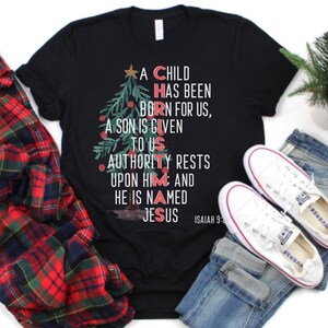 May include: Black t-shirt with a Christmas tree design and the words "A Child Has Been Born For Us, A Son Is Given To Us, Authority Rests Upon Him And He Is Named Jesus" and "Isaiah 9:6".