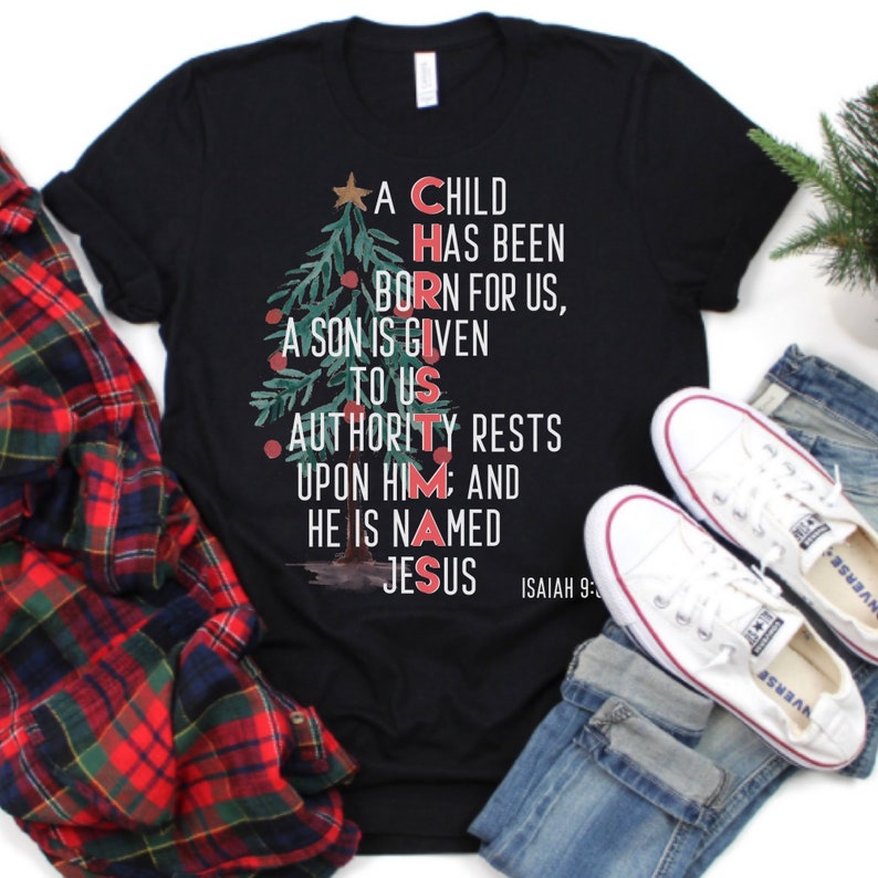 May include: Black t-shirt with a Christmas tree design and the words "A Child Has Been Born For Us, A Son Is Given To Us, Authority Rests Upon Him And He Is Named Jesus" and "Isaiah 9:6".