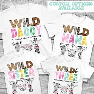 May include: Four white t-shirts with a wild animal theme. The shirts feature the words "Wild Daddy", "Wild Mama", "Wild Sister", and "Wild & Three". Each shirt has a colorful design with a zebra, lion, and giraffe.