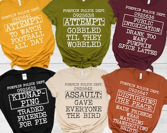 May include: Six different t-shirts with a fall theme. Each shirt has a different design with a police department theme. The shirts are in various colors, including black, brown, green, red, and yellow.