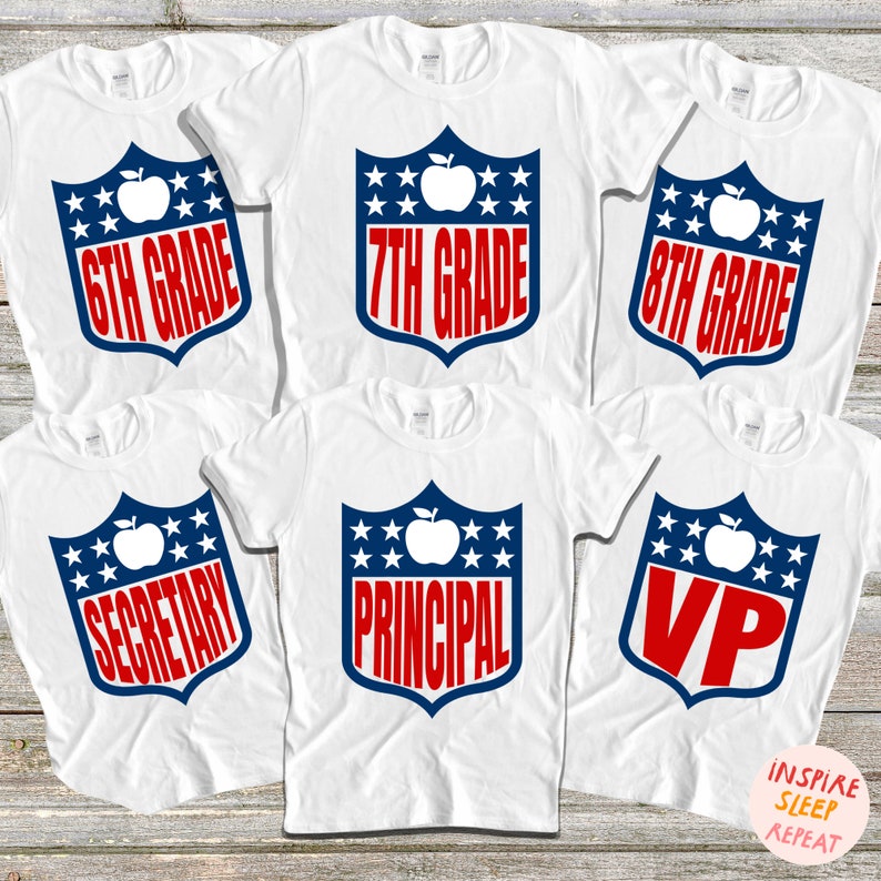 May include: Six white t-shirts with red, white, and blue designs. The designs feature a shield with an apple and stars. The text on the shirts reads "6th Grade", "7th Grade", "8th Grade", "Secretary", "Principal", and "VP".