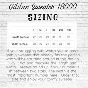 May include: A white brick wall background with a sizing chart for a Gildan 18000 sweater. The chart shows length and width measurements in inches for sizes S to 3XL. Text advises measuring a sweater for the best fit.