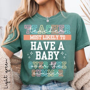 May include: Light green t-shirt with the text "TEACHER MOST LIKELY TO HAVE A BABY OVER THE SUMMER" in colorful block letters. The shirt has a crew neck and short sleeves. The text is in white, pink, blue, orange, and green.