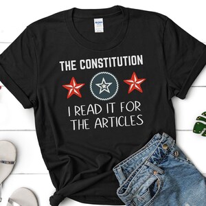 May include: Black t-shirt with white text that reads "The Constitution I read it for the articles". There are three red stars with white outlines and a blue star with a white outline in a circle.
