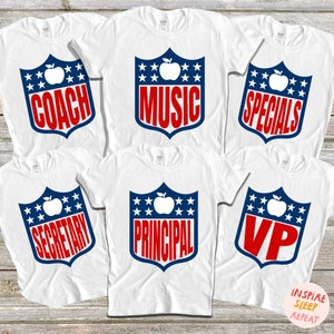 May include: Six white t-shirts with a blue and red shield design featuring a white apple and text. The text on the shirts reads "Coach", "Music", "Specials", "Secretary", "Principal", and "VP".