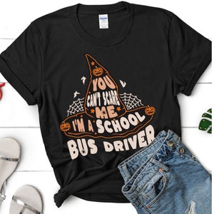 May include: Black t-shirt with a witch hat graphic and the text "You can't scare me I'm a school bus driver".