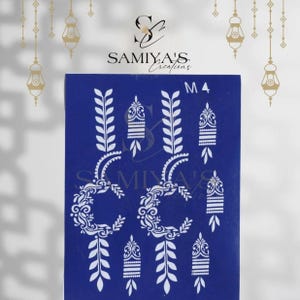 May include: A blue stencil sheet featuring white henna-style designs. The sheet includes leaf and floral patterns, along with the text "SAMIYA'S Creations" and "M4". Decorative hanging lanterns are in the background.