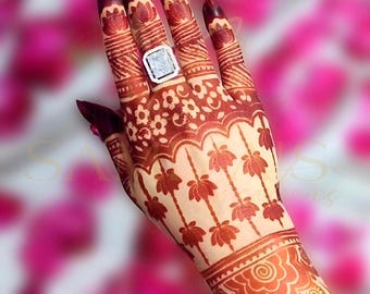 May include: A hand adorned with intricate henna designs in shades of red-brown. The henna art features floral patterns, including lotus flowers and detailed line work. The text "Henna Stencil SC206" is visible. A silver ring with a square stone is on the ring finger.