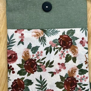 May include: A green canvas pouch with a floral fabric lining. The pouch has a single black button closure and a white background with pink and brown floral designs.