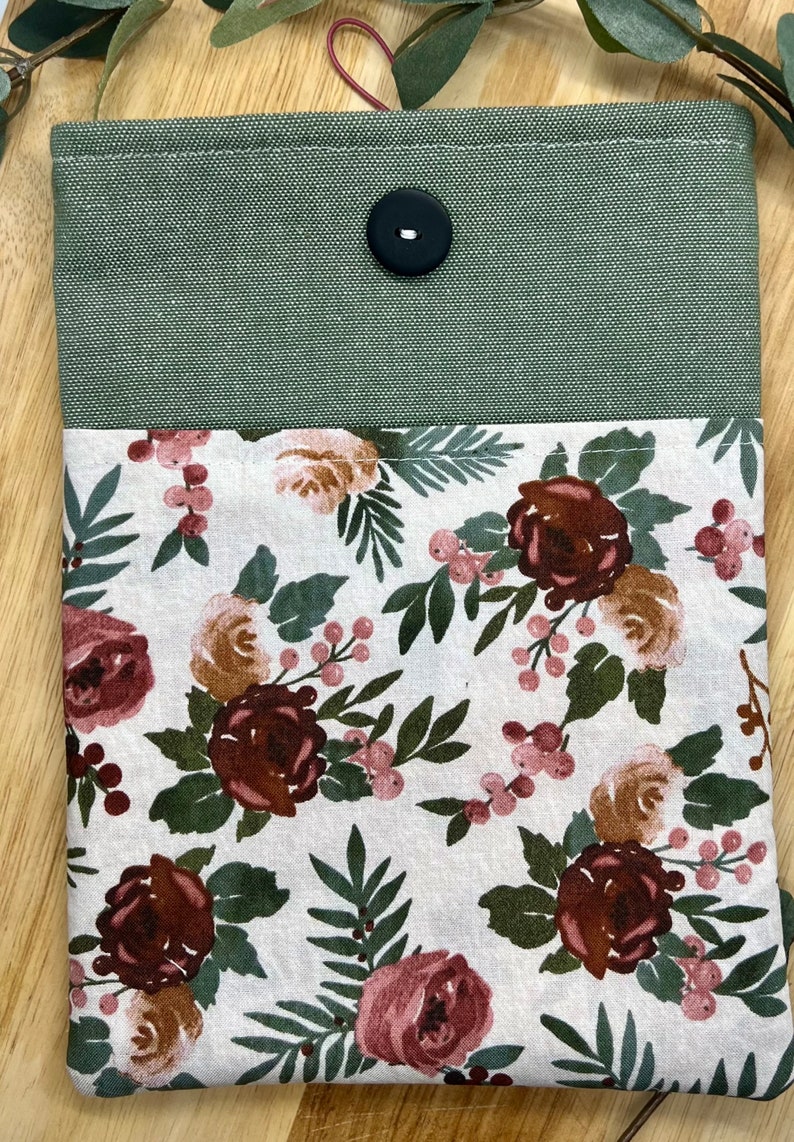 May include: A green canvas pouch with a floral fabric lining. The pouch has a single black button closure and a white background with pink and brown floral designs.