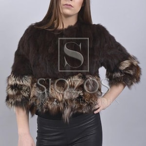May include: A brown fur jacket with a silver fox trim. The jacket has a short, cropped style and is made of soft, luxurious fur.