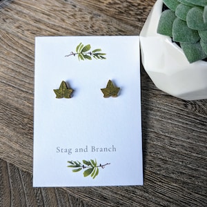 May include: A pair of wooden leaf earrings in a light green color. The earrings are displayed on a white card with the text "Stag and Branch".