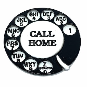 May include: Black and white rotary phone dial with the words "CALL HOME" in the centre. The dial has numbers 1 through 0 and letters A through Z.