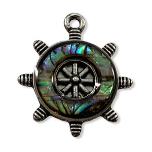 May include: A silver-toned ship's wheel charm with a mother-of-pearl inlay. The wheel has eight spokes and a central hub. The mother-of-pearl inlay is iridescent with shades of green, blue, and purple.