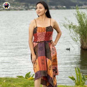 May include: A patchwork midi dress with a square neckline and spaghetti straps. The dress features a mix of colors including orange, red, purple, and brown. The skirt has a handkerchief hemline. The dress is made of a lightweight fabric.