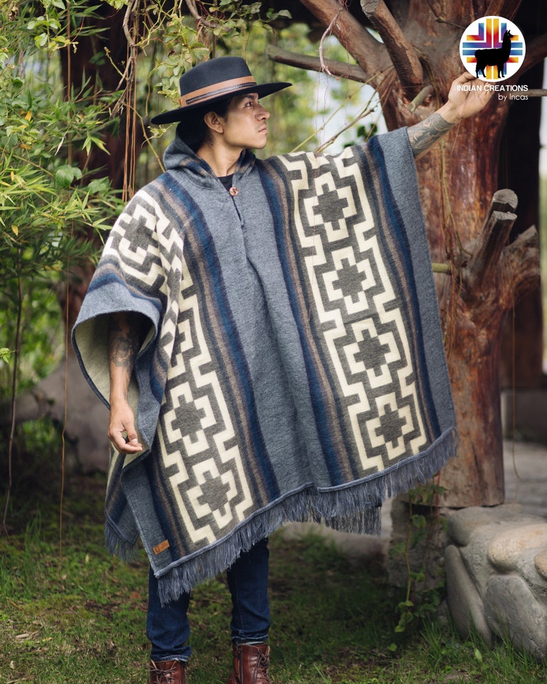 May include: A gray alpaca wool poncho with a geometric pattern and fringe. The poncho is worn by a person wearing a black hat and blue jeans. The poncho has a label that says "Indian Creations by Incas".