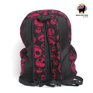 K&ouml;nnte beinhalten: Ein schwarzer Rucksack mit verstellbaren Tr&auml;gern. Der Rucksack besteht aus einem schwarzen Stoff mit einem pinkfarbenen und schwarzen Muster von Jack Skellingtons Gesicht aus dem Film Nightmare Before Christmas.