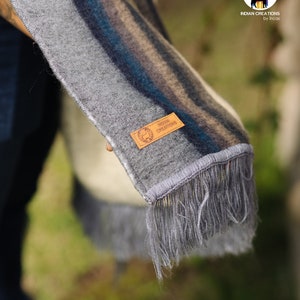 May include: Gray and blue striped alpaca wool scarf with fringe. The scarf has a brown leather tag with the text "INDIAN CREATIONS by Incas".