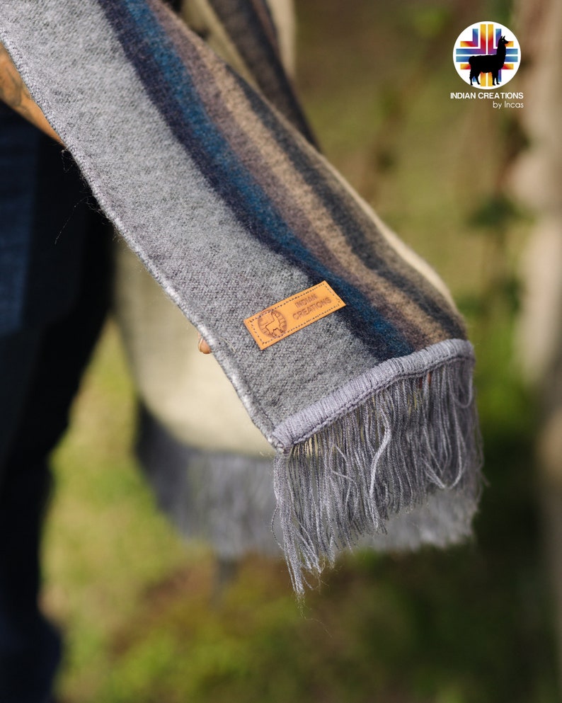 May include: Gray and blue striped alpaca wool scarf with fringe. The scarf has a brown leather tag with the text "INDIAN CREATIONS by Incas".