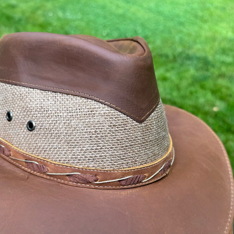 May include: A brown leather and woven straw cowboy hat with a wide brim.