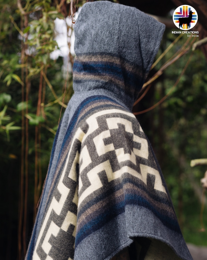 May include: A gray hooded poncho with a white and gray geometric pattern and blue stripes. The poncho is made of alpaca wool and is a traditional garment from the Andes Mountains.