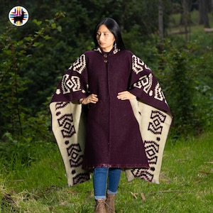 Peut inclure: Une femme porte un manteau violet foncé avec un poncho crème. Le poncho présente un motif géométrique crème et violet foncé. Le manteau a une fermeture à boutons et un ourlet à franges. L'arrière-plan est une forêt verte.