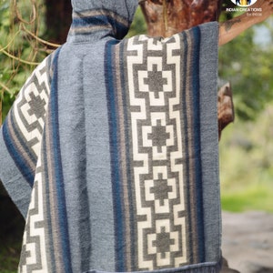 May include: A gray hooded poncho with a geometric pattern in white and black. The poncho has a fringe border and is made of a soft, woven fabric.